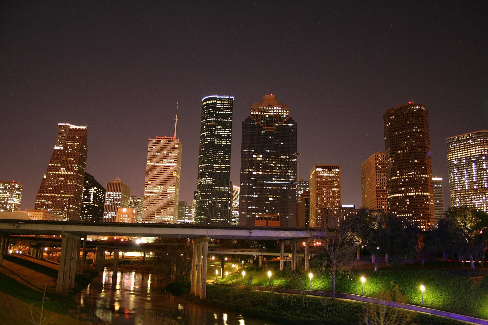 The downtown Houston skyline at night, lit towers above Buffalo Bayou